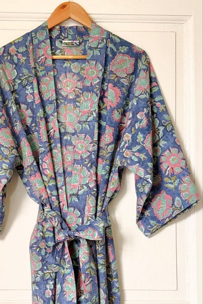 Floral patterned robe hanging on a door next to a bathtub.