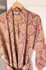 Pink patterned robe on a wooden hanger against a white background