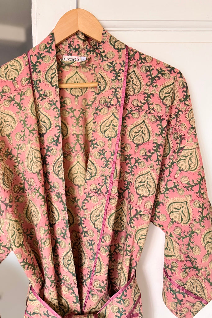 Pink patterned robe on a wooden hanger against a white background