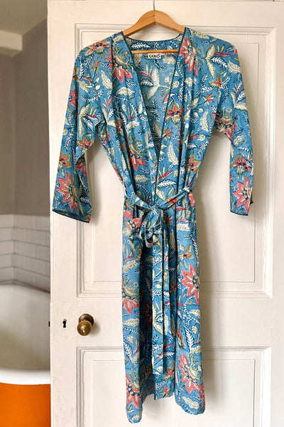 Floral patterned robe hanging on a door next to a bathtub.