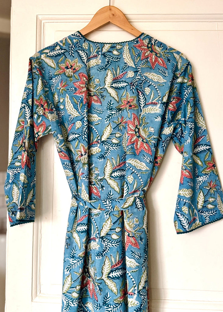 Floral-patterned dress on a hanger against a white door background