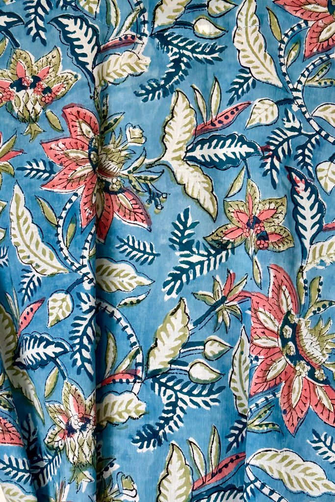 Close-up of a floral fabric pattern with pink, red, and green flowers on a blue background.