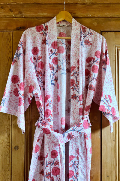 Long pink and white floral kimono hanging against wooden wall