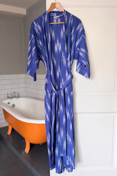 Blue ikat woven robe hanging in a bathroom with an orange bathtub.