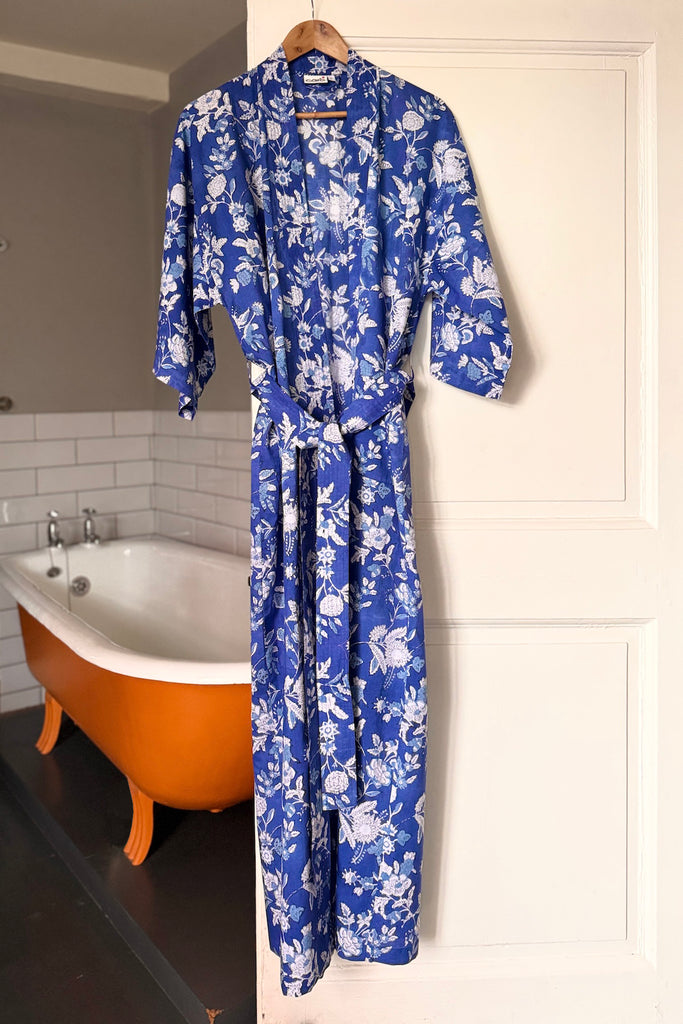Blue floral robe hanging on a hook in a bathroom with a bathtub.