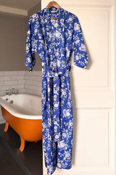 Blue floral robe hanging on a hook in a bathroom with a bathtub.