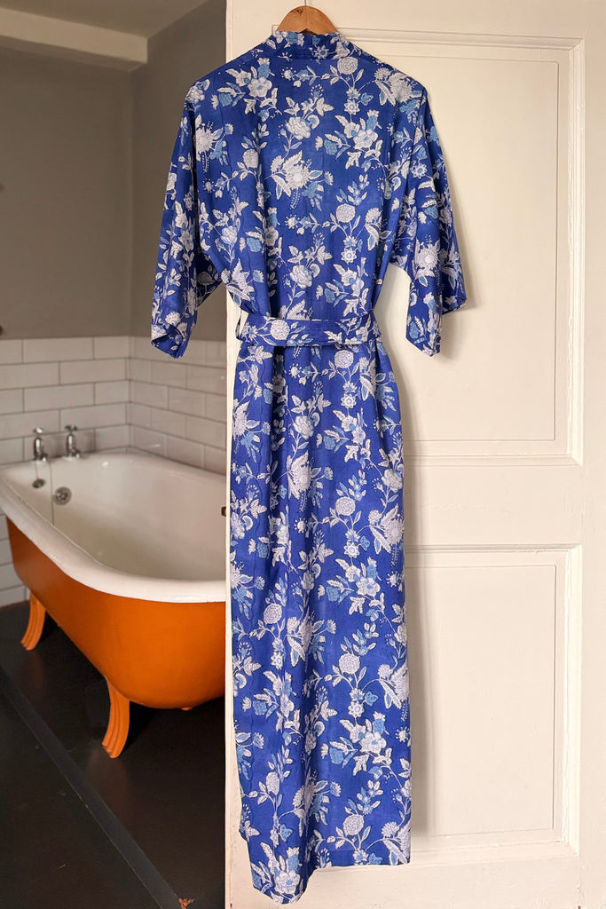 Blue floral robe hanging on a white door with an orange bathtub in the background.