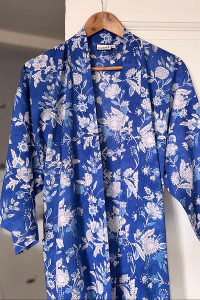 Blue floral robe hanging on a wooden hanger against a white wall.