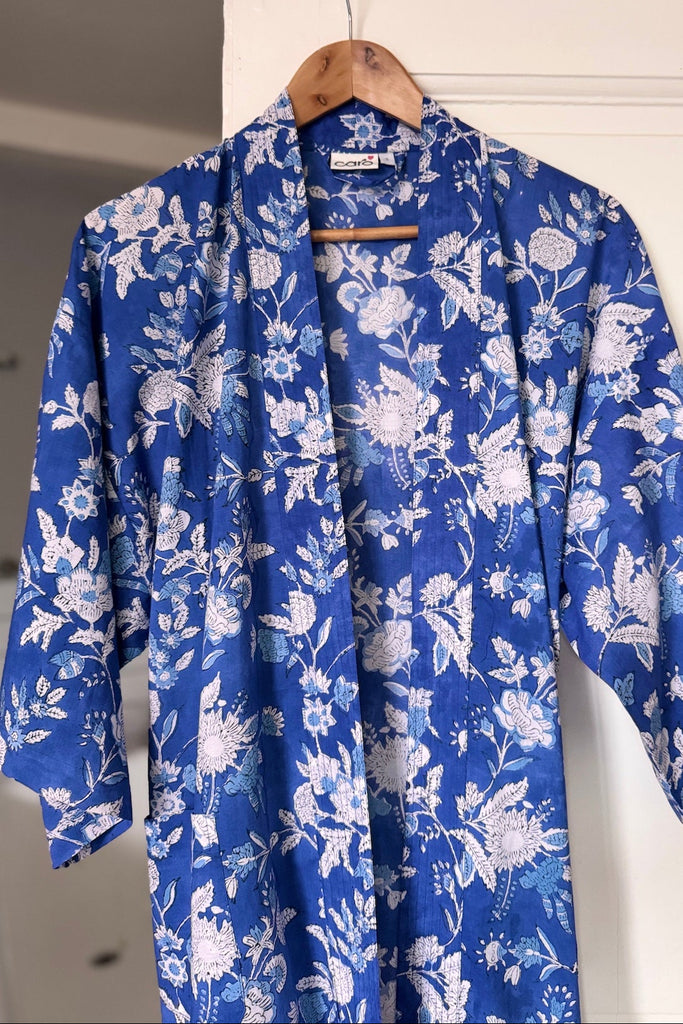 Blue floral robe hanging on a wooden hanger against a white wall.