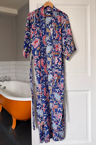 Floral patterned robe hanging on a door in a bathroom.