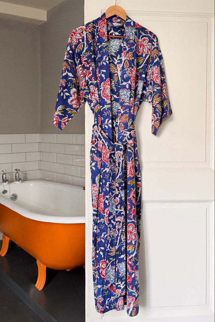 Floral patterned robe hanging on a door with a bathtub in the background
