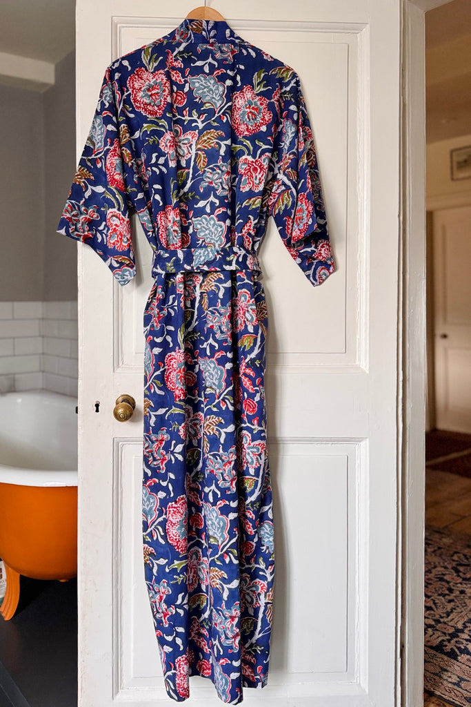 Floral-patterned robe hanging on a white door in a bathroom.