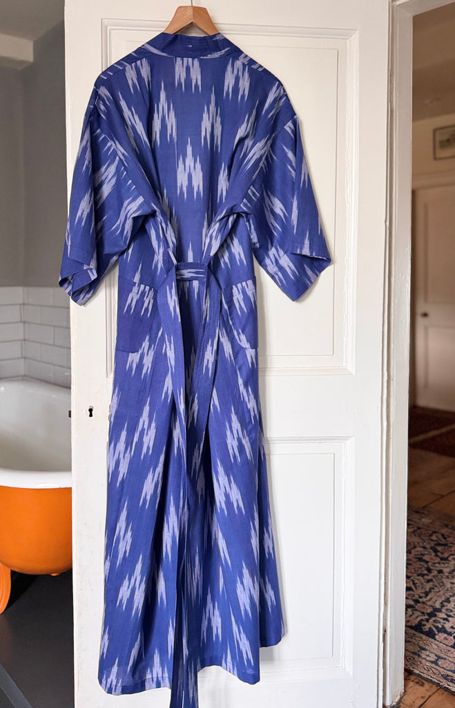 Blue patterned long kimono robe hanging on a door in a bathroom.