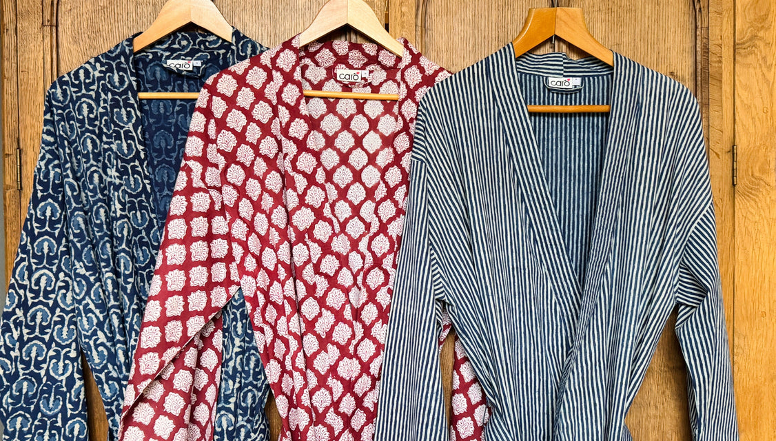 Three patterned mens kimonos on hangers against a wooden background