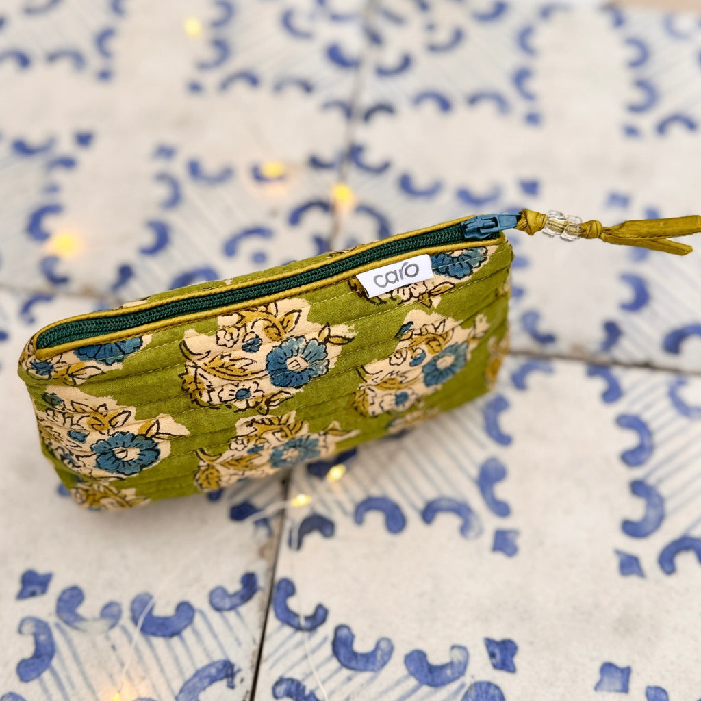 Green floral-patterned pouch with a visible brand label on a decorative background