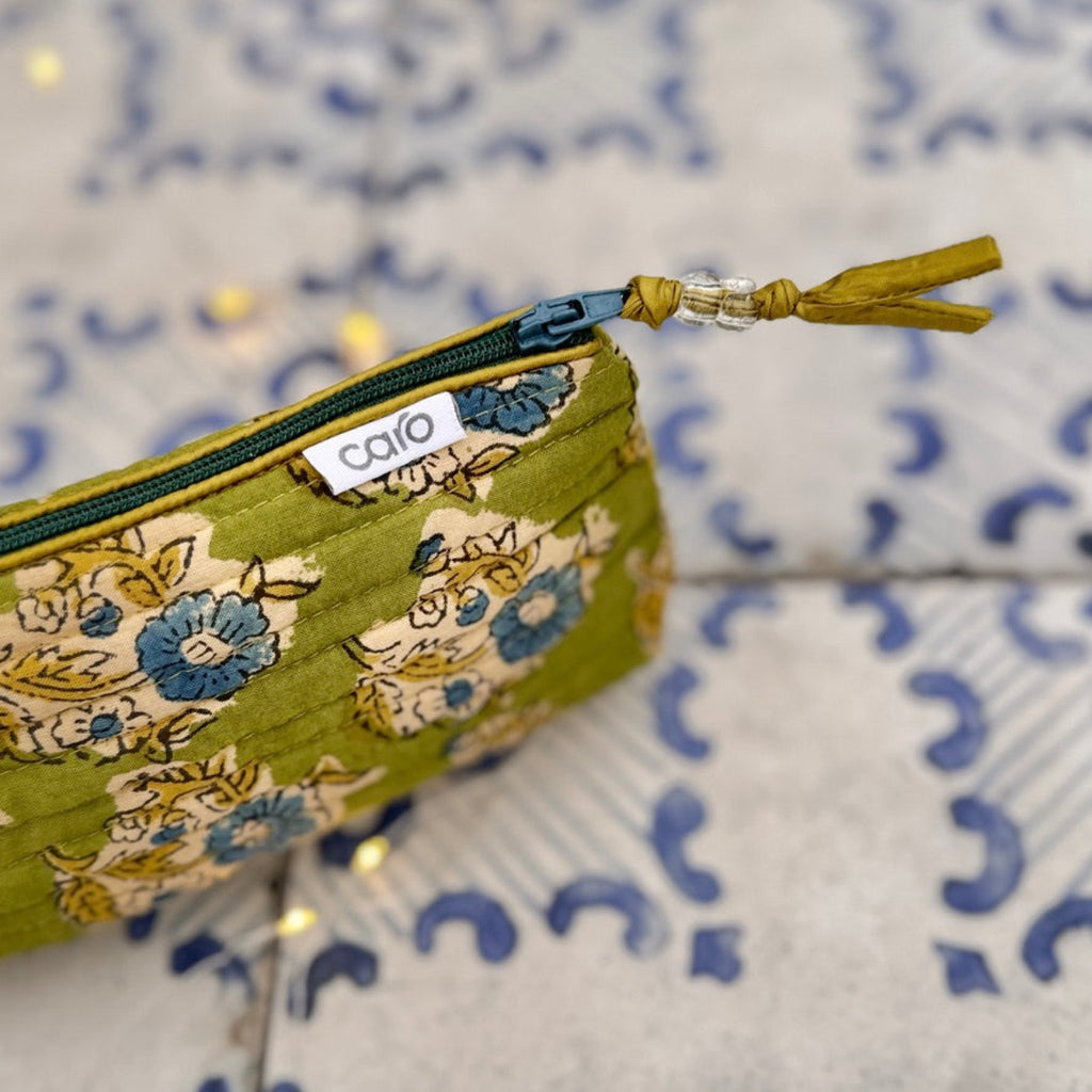 Fabric pouch with floral pattern and visible brand logo on a textured background