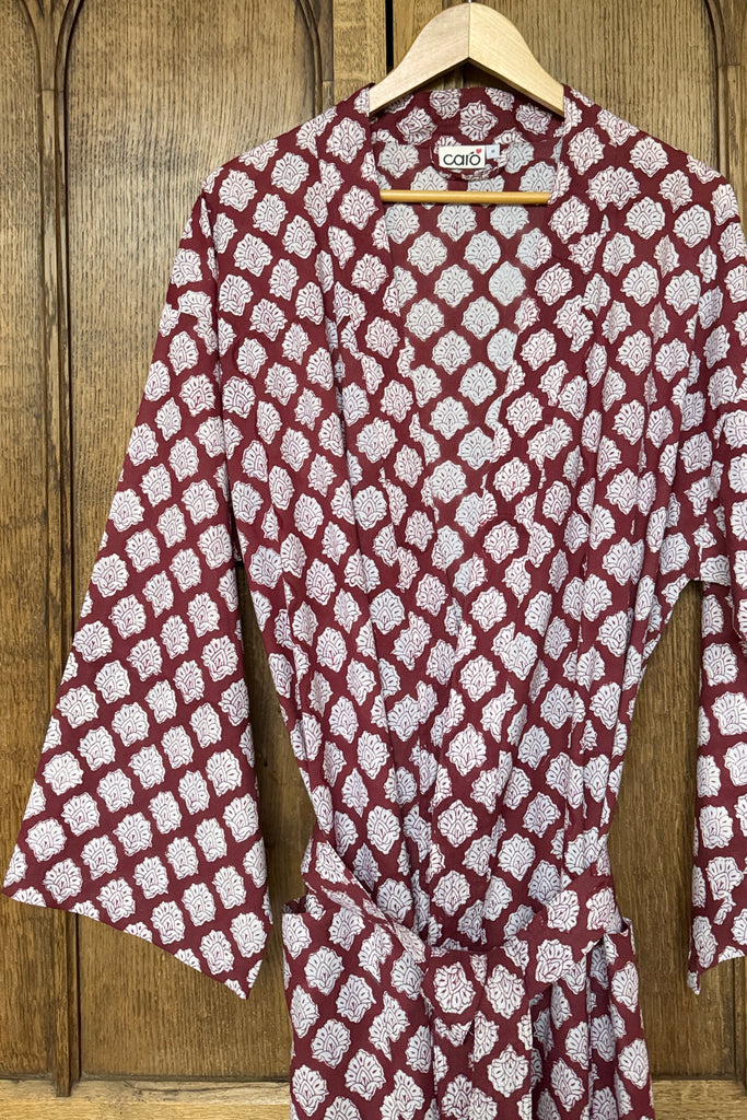 Maroon and white patterned shirt on a hanger against a wooden background