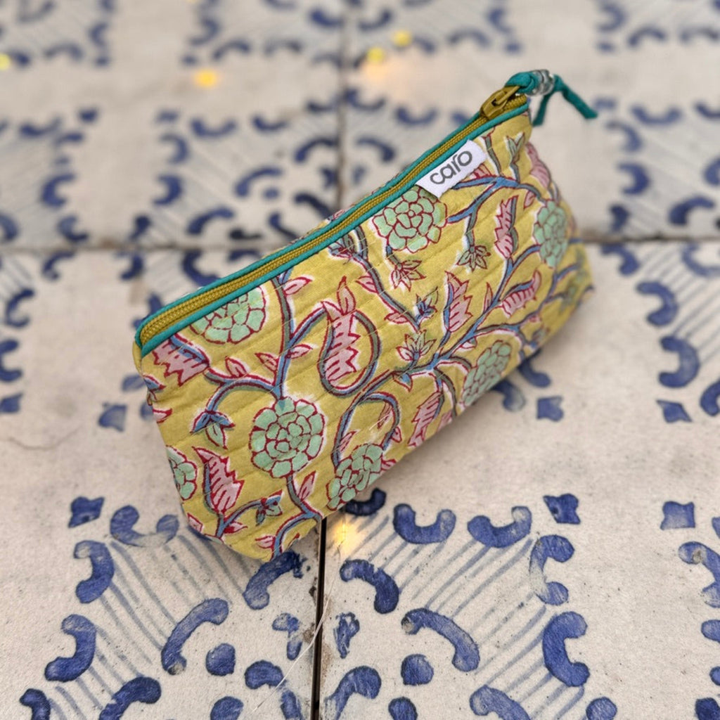 Yellow floral-patterned pouch on a textured surface with blue and white design