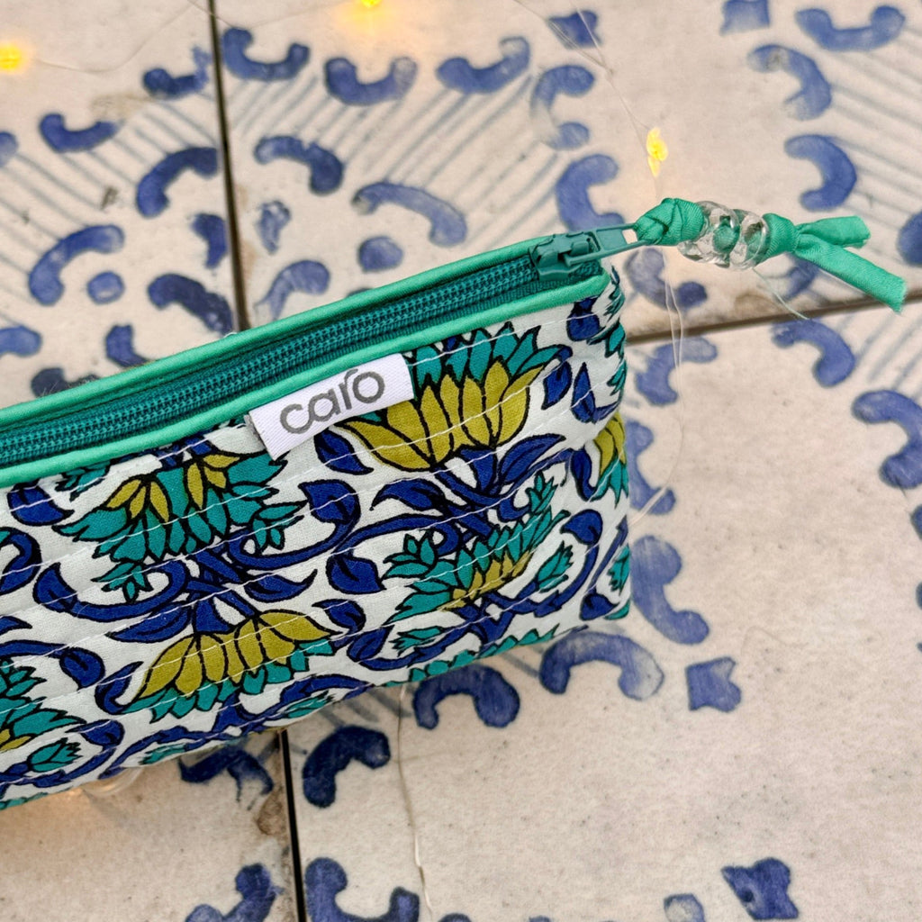 Fabric pouch with floral pattern and green zipper on a textured surface