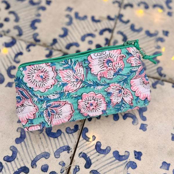 turquoise and pink floral quilted make up bag on blue and white tile