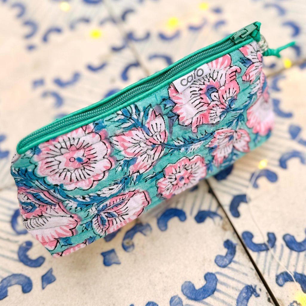 Floral patterned make up case with green zipper on a decorative tile background