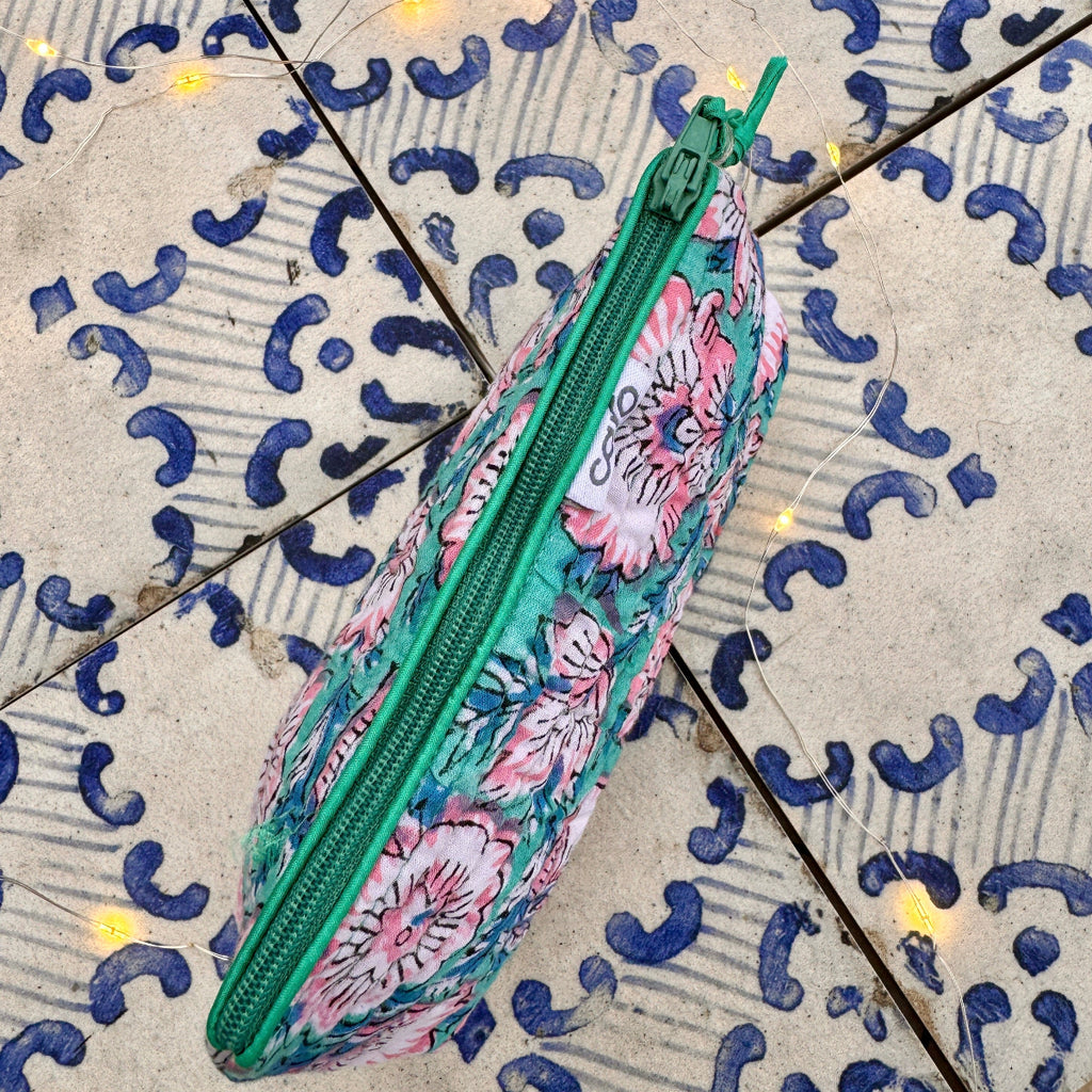 Floral patterned pencil case with green zipper on a decorative tile background