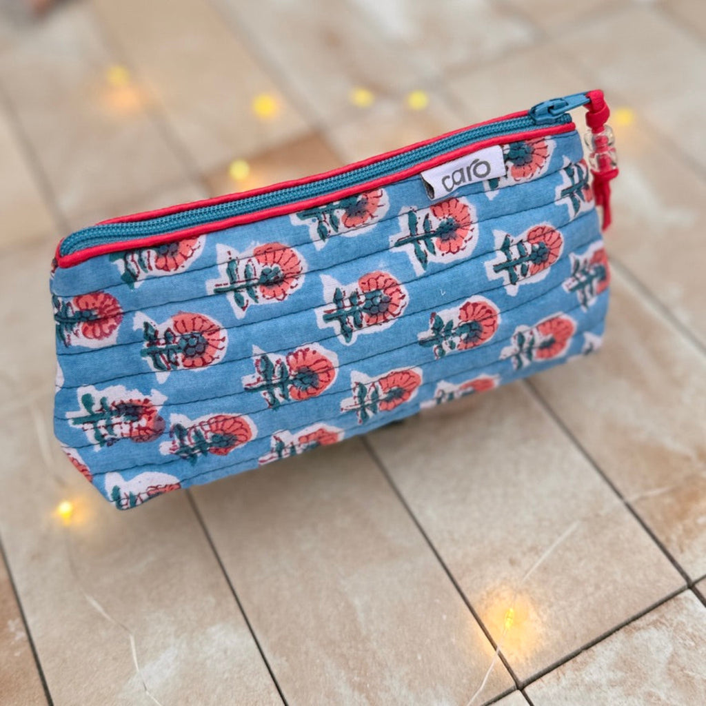 Floral patterned small cosmetic bag with red zipper on a tiled floor