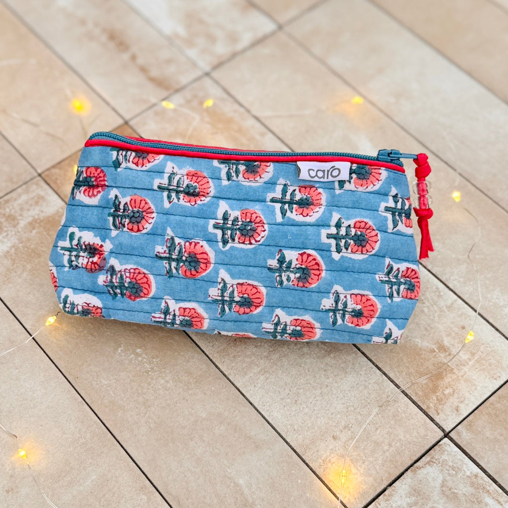 Blue make up bag with red zipper on a beige tiles
