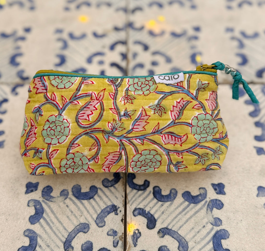 Yellow twining floral print cosmetic bag on blue patterned tile