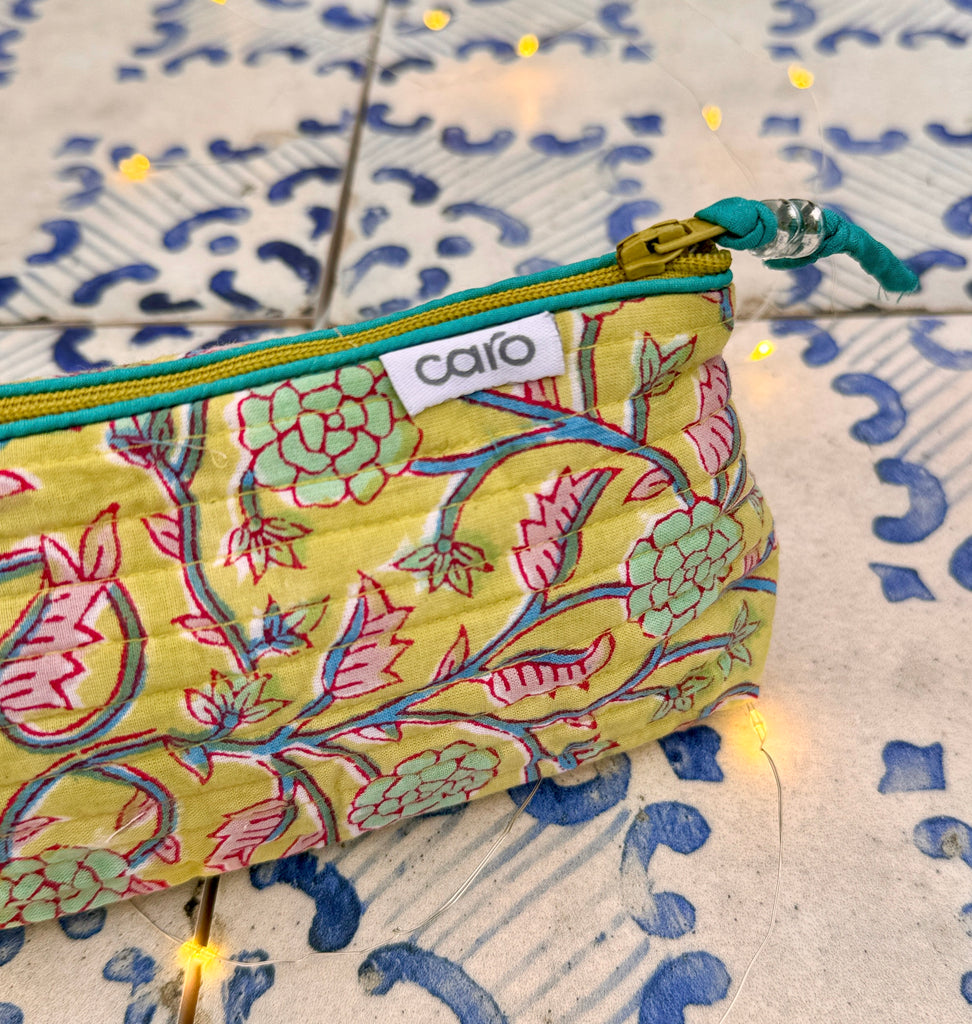 Close up of end of yellow twining floral print cosmetic bag on blue patterned tile