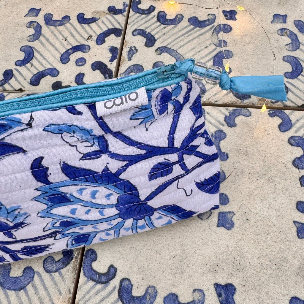 Blue and white floral patterned cosmetic bag with a visible brand logo on a textured surface.