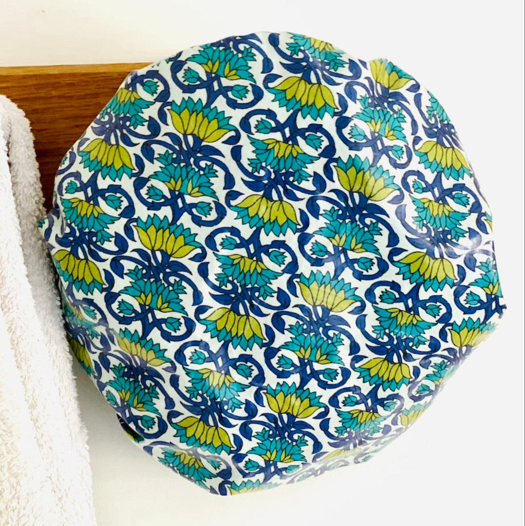 blue, turquoise and green trellis floral shower cap hanging from a wooden peg