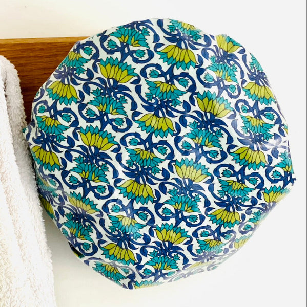 blue, turquoise and green trellis floral shower cap hanging from a wooden peg