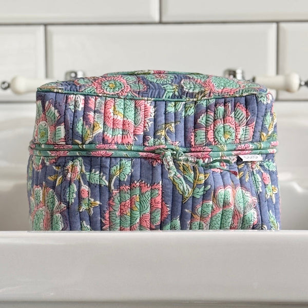 Floral-patterned fabric vanity toiletry bag on a white surface with a neutral background