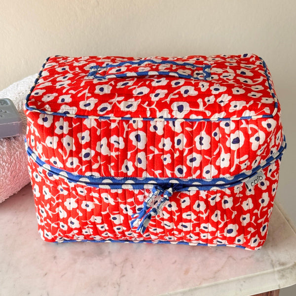 Close up of 'Antibes' orange, blue and white floral quilted cotton vanity case washbag trimmed with blue and white polka dot binding.