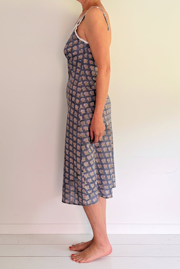 Woman wearing a blue floral dress against a white wall