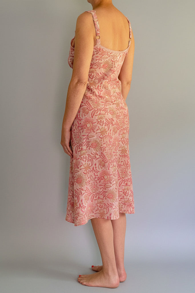 Person wearing a pink floral dress standing against a white wall.