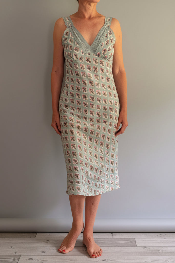 Woman wearing a patterned dress standing against a plain background
