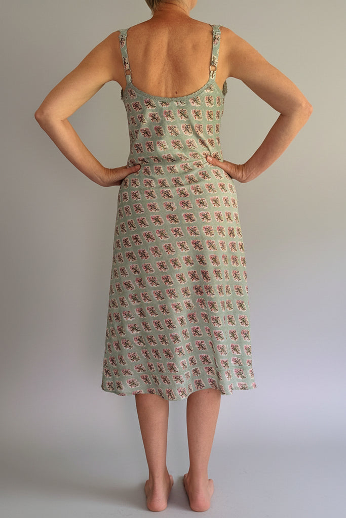 Person wearing a patterned dress with their back to the camera on a plain background