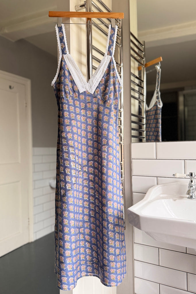 Blue patterned dress hanging on a rack in a bathroom.