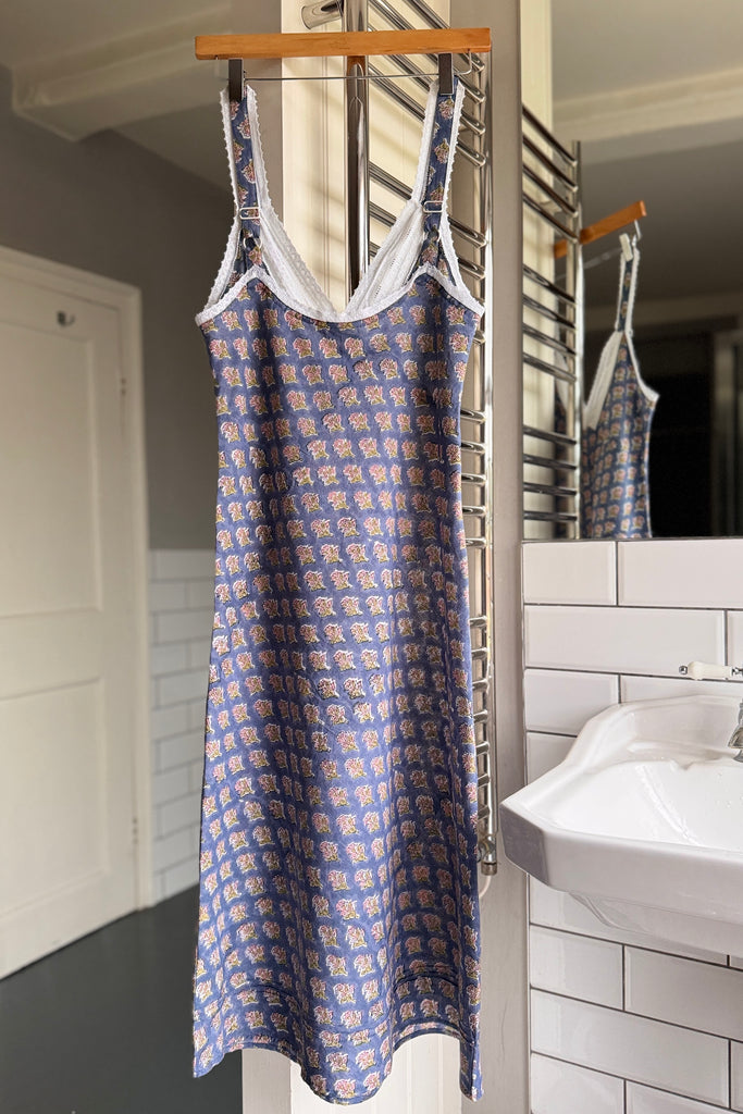 Blue floral dress hanging on a rack in a bathroom.