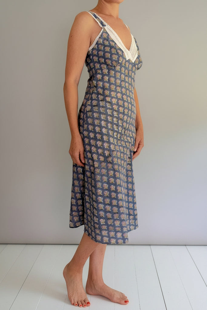 Woman wearing a patterned slip dress against a plain background