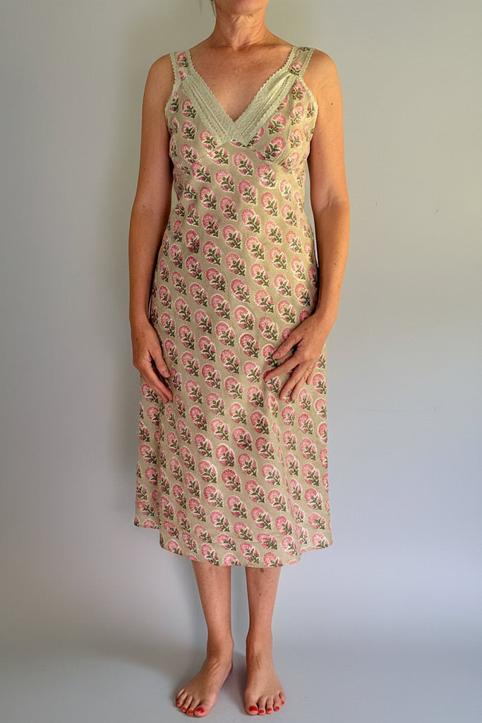 Person wearing a floral dress standing on a wooden stool against a plain background