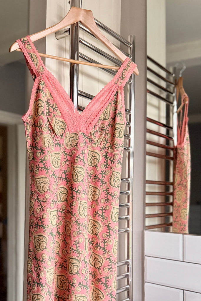 Pink patterned night dress hanging on a rack with a mirror reflection.
