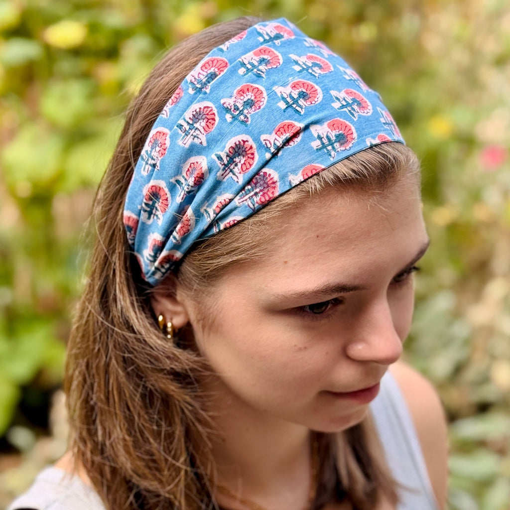 Woman wearing a blue headband with red floral patterns outdoors.