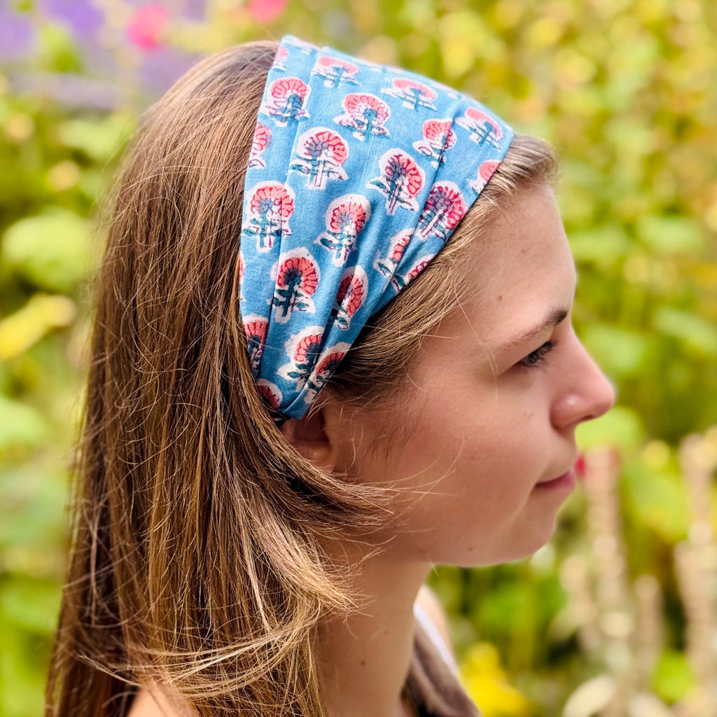 Woman wearing a blue floral patterned headband with a blurred green background