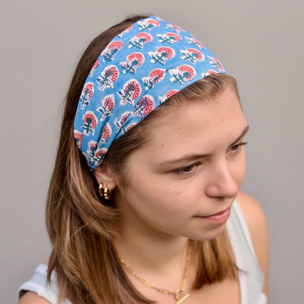 Person wearing a blue headband with red and white patterns against a natural background