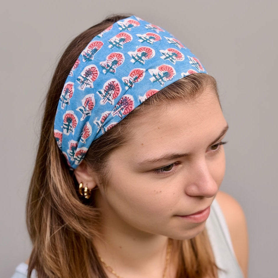 Person wearing a blue headband with red and white patterns against a natural background