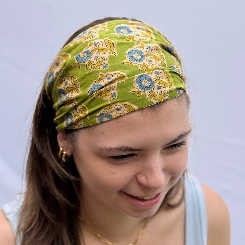 Woman wearing a green patterned headband against a light blue background