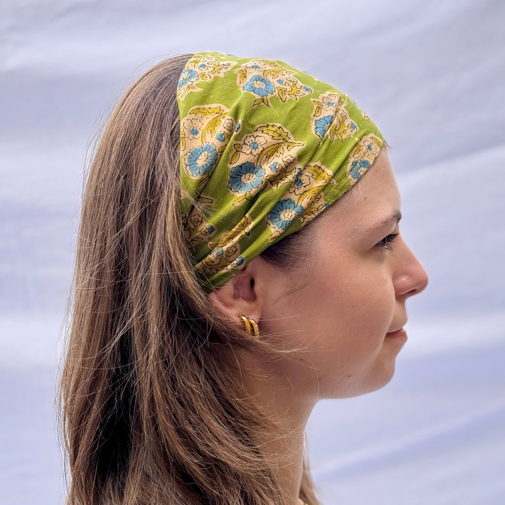 Woman wearing a green patterned headband against a light background